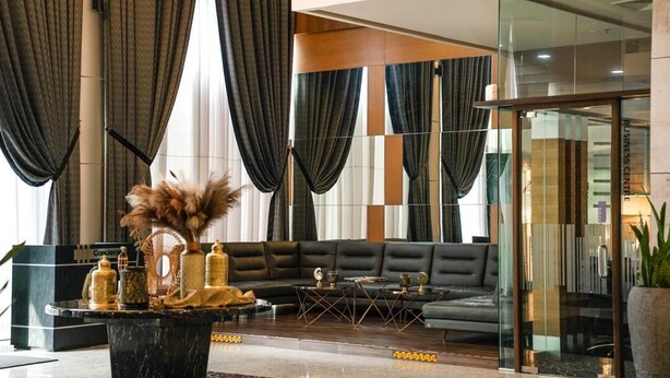 A modern lobby with a black leather sofa, a marble coffee table, and a reception desk. - New World Suites (Bintulu)