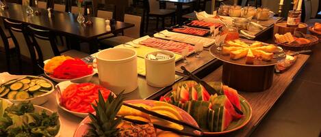 Una mesa de buffet con frutas, verduras y quesos variados.