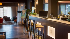 Zona de bar moderna con sillas de madera, una computadora portátil y una barra.