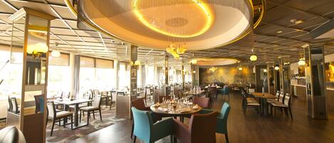Ein geräumiges Restaurant mit hohen Decken, modernen Kronleuchtern und verschiedenen Sitzmöglichkeiten.