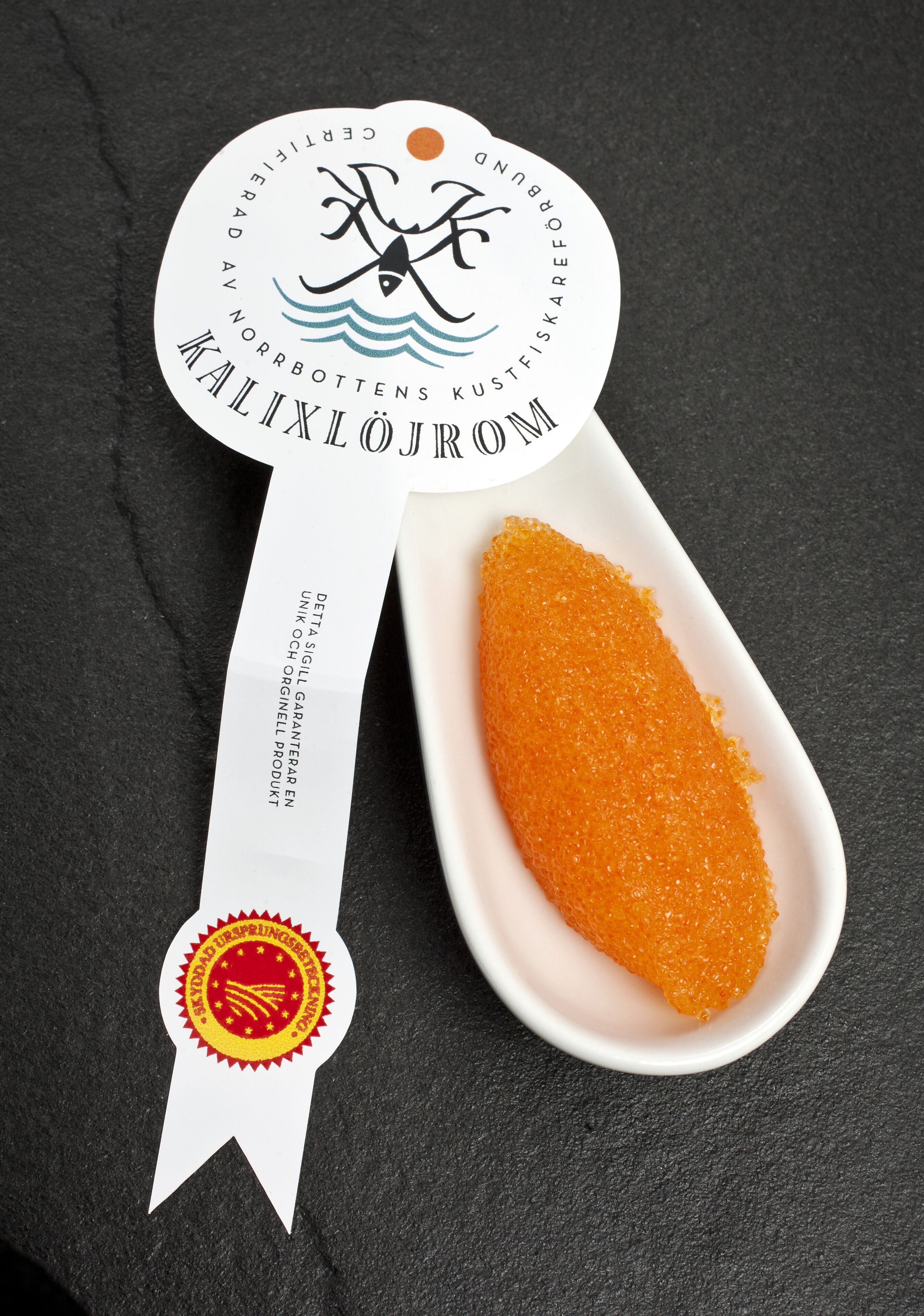 Un certificat agrémenté d’un ruban et accompagné d’une cuillère de caviar d’orange.