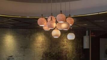 Un interior de restaurante con mesas redondas, sillas y una planta decorativa central.