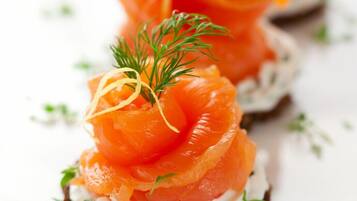 A close-up of a food item, likely a type of appetizer, with salmon and cream on a base, garnished with herbs.