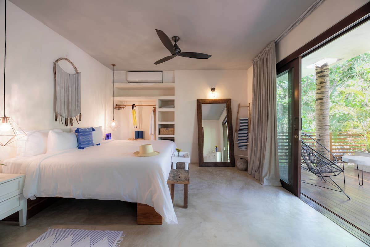 Une chambre à coucher avec un lit, une table de chevet et une grande fenêtre donnant sur un paysage verdoyant.