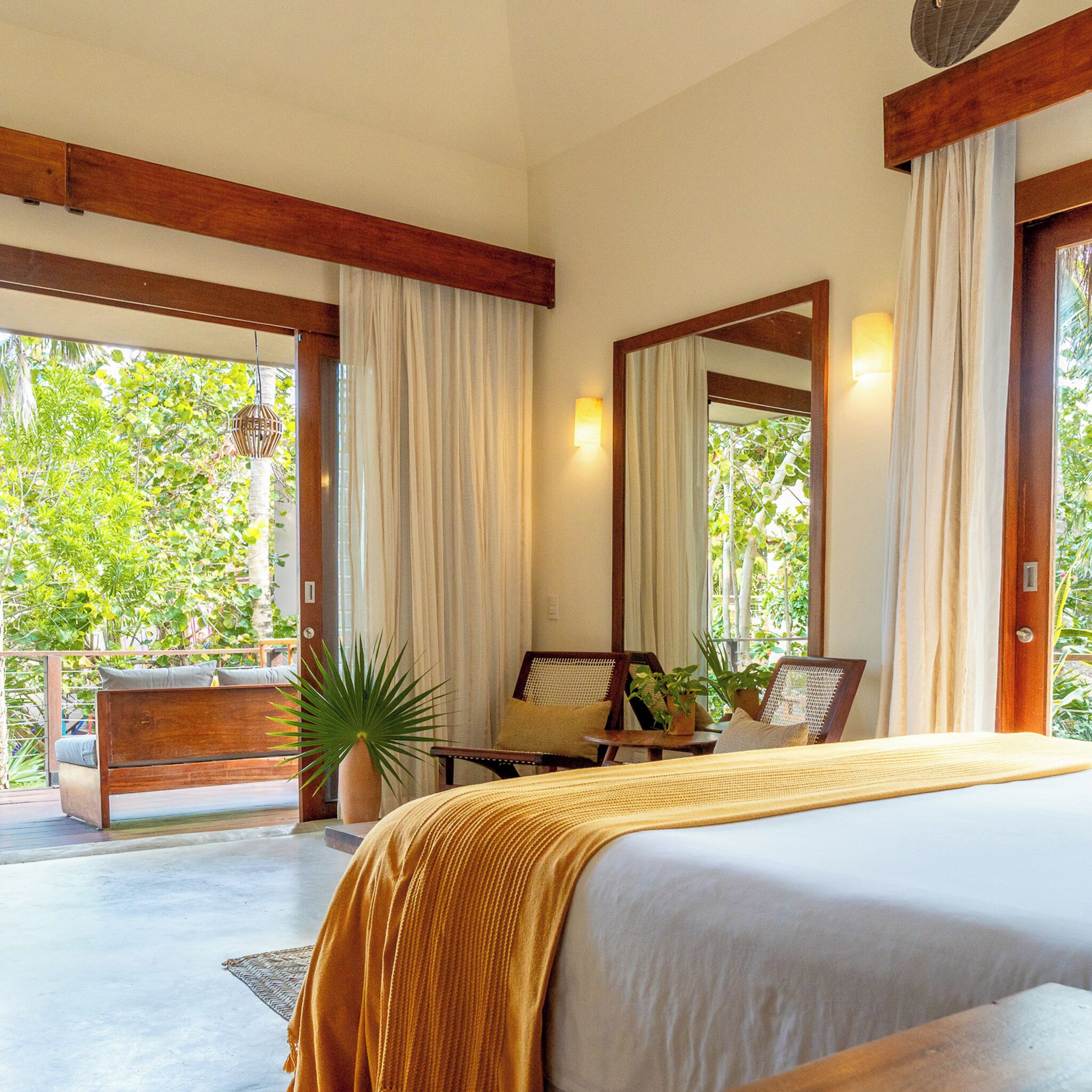 Un dormitorio con una cama grande, techo de madera, ventana con cortinas y vistas al exterior.