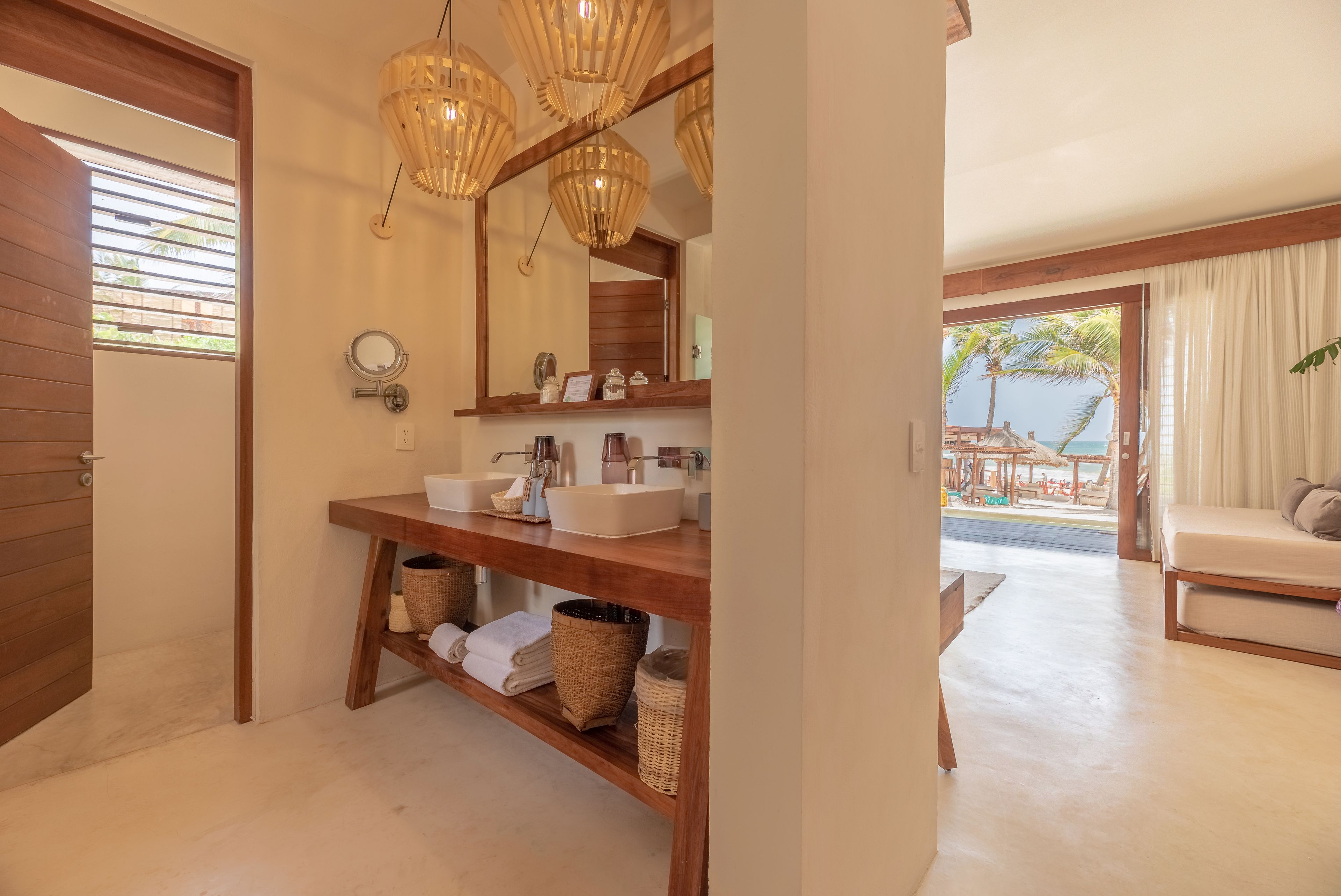 Un baño moderno con estantes de madera, un espejo grande y vistas al área de estar exterior.