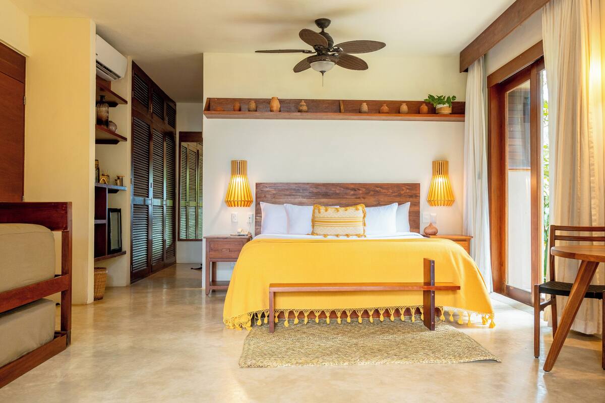 Une chambre à coucher avec un lit, des lampes de chevet, un ventilateur de plafond et une vue sur l’extérieur.