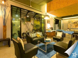 A modern living room with leather sofas, a glass partition, and a dining area with a blue tablecloth. - Sea Front Home Boutique - Patong Beach (Patong)