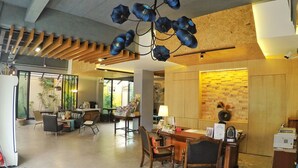 Un vestíbulo espacioso con un mostrador de recepción de madera, un candelabro y una pared con diseño de ladrillo.