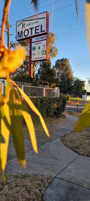 A motel sign with amenities including free Wi-Fi, parking, and a golf course. - Golf Links Motel (West Tamworth)