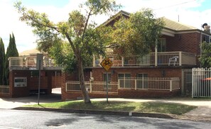 A two-story building with a bicycle sign, a gated entrance, and a clear view of the street. - Golf Links Motel (West Tamworth)
