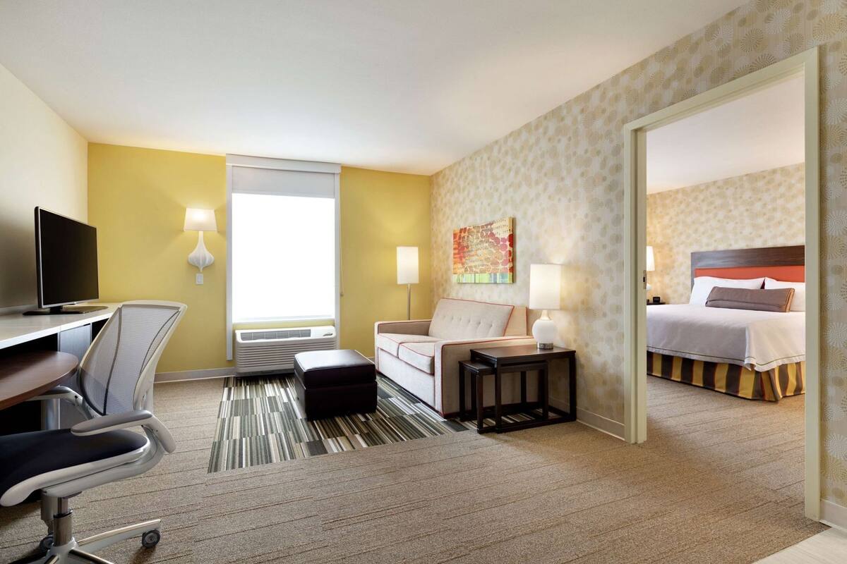 Une chambre d’hôtel comprenant un lit, un bureau avec une chaise, un canapé, une télévision et une fenêtre.