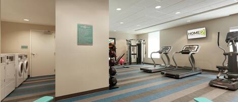 A gym with treadmills, elliptical machines, and a wall-mounted sign reading 'HOME2'.