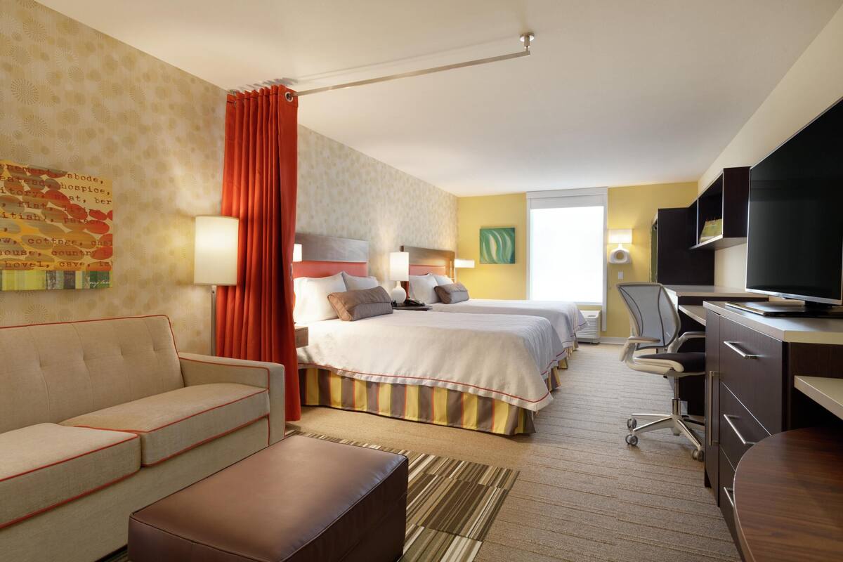 Une chambre d’hôtel avec un lit, un canapé, un bureau, une télévision et une lampe.
