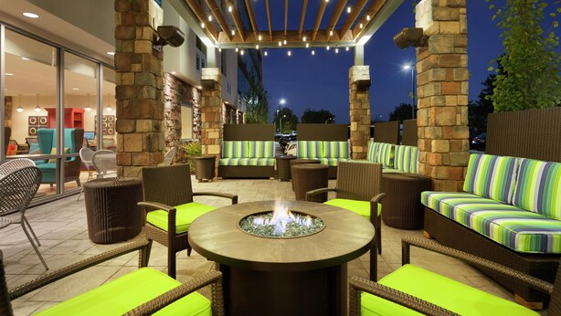 An outdoor patio area with seating, a fire pit, and a stone wall. - Home2 Suites by Hilton Seattle Airport (Tukwila)