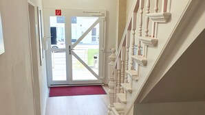 A hotel hallway with a wooden floor, a red carpet, and a staircase with white balusters. - Aparthotel Sanni  (Bremen)