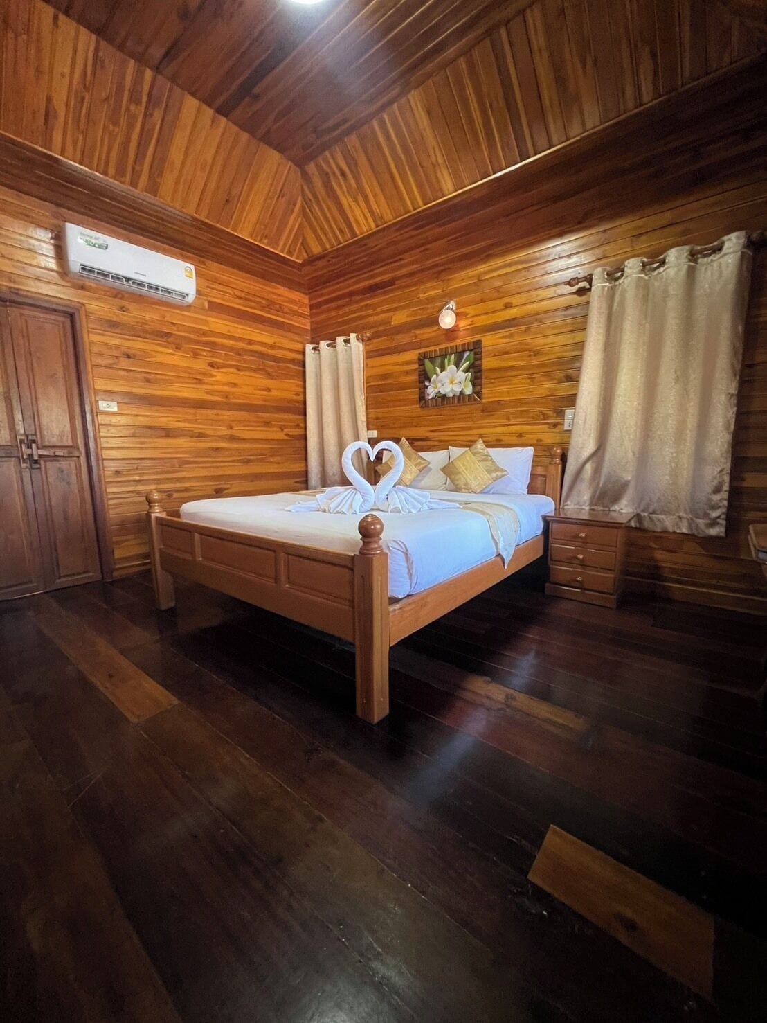 Una stanza con rivestimenti in legno, un letto, un armadio e un condizionatore d'aria a muro.