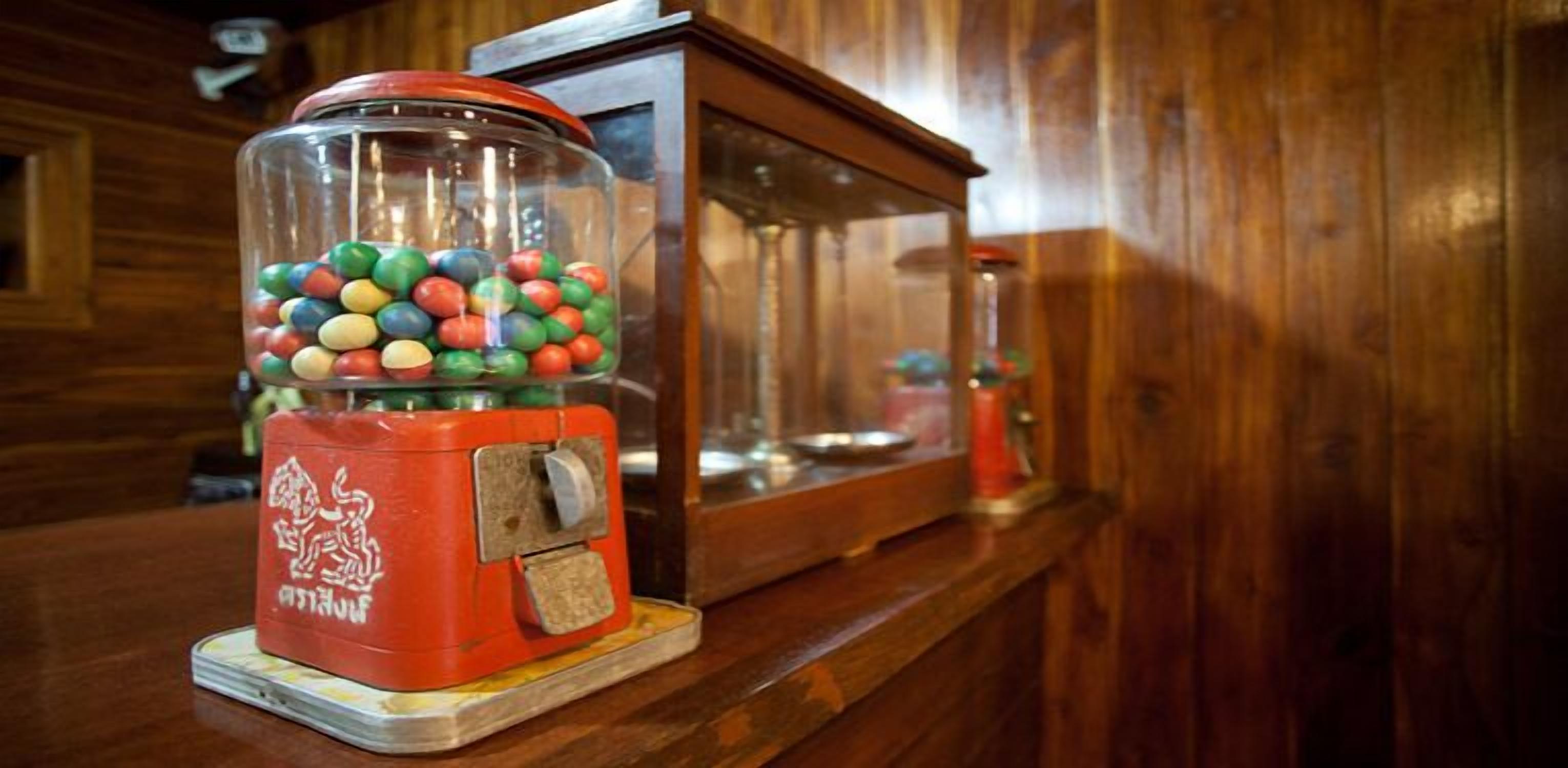 Une machine à chewing-gum remplie de chewing-gums colorés, posée sur un comptoir en bois.