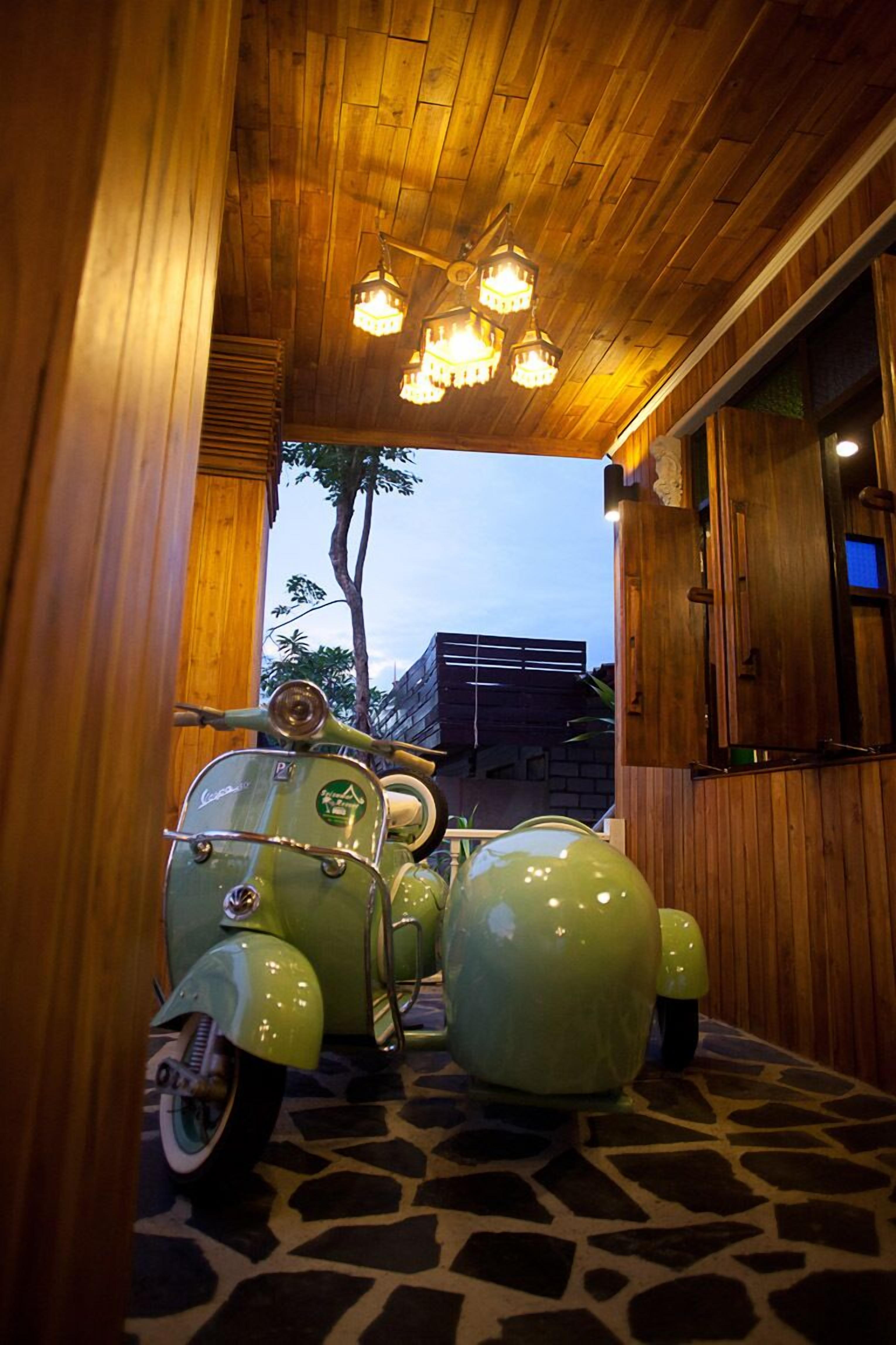Een houten interieur met een oldtimer scooter en een kroonluchter.