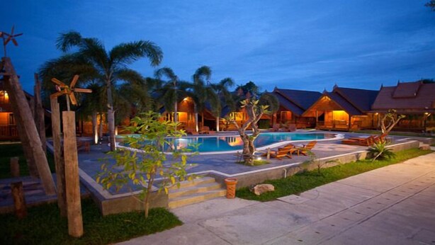 Un resort con piscina, palmeras y edificios de estilo tradicional.