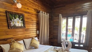 Una habitación tipo cabaña de madera con una cama, cortinas y una ventana con vistas.
