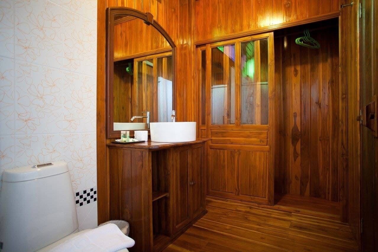 Un bagno in legno con lavandino, specchio e servizi igienici.