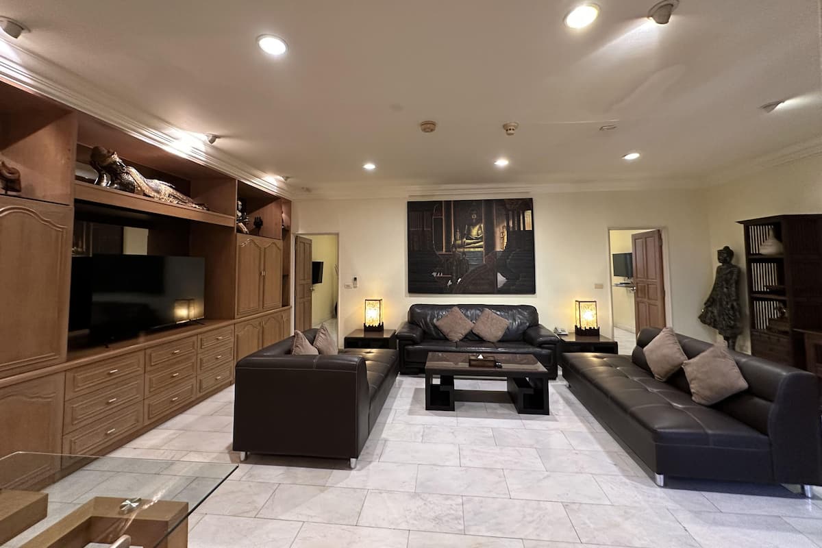 A modern living room with a sofa set, a coffee table, a TV, and a large painting on the wall.