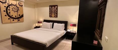 A hotel room with a bed, two bedside tables, a ceiling fan, and wall art.