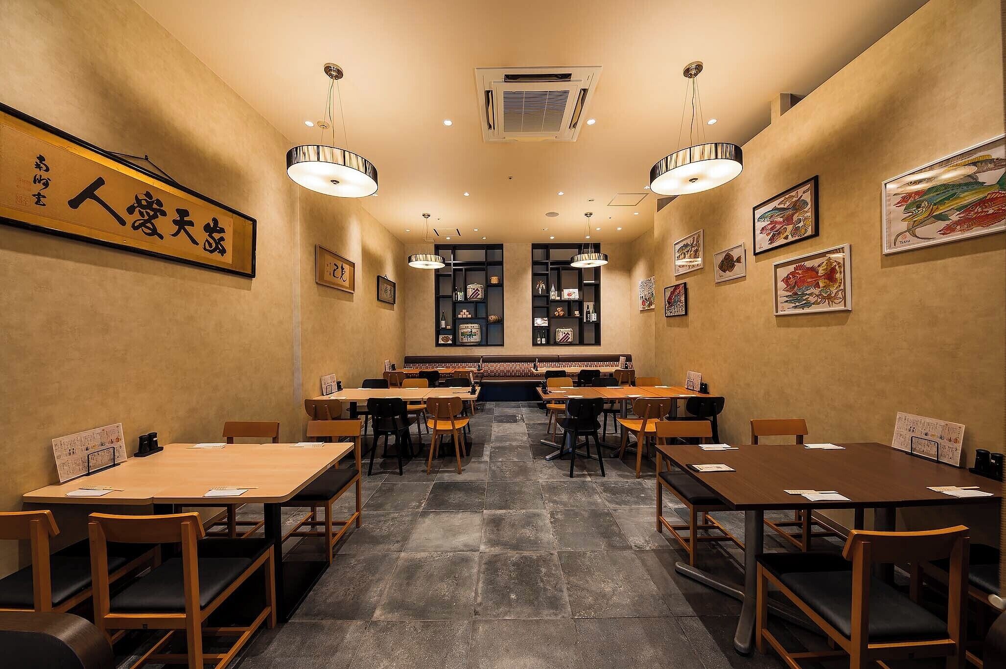 Interior de restaurante con varias mesas y sillas, piso de baldosas y obras de arte colgadas en la pared.