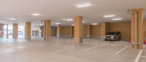 A spacious indoor parking area with concrete flooring and beige pillars.