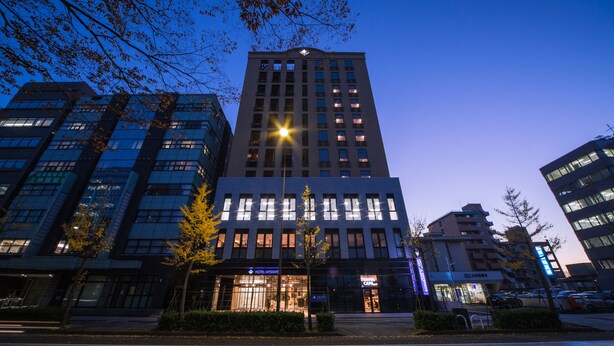 Un hôtel moderne, avec plusieurs étages, de grandes fenêtres et une entrée imposante.