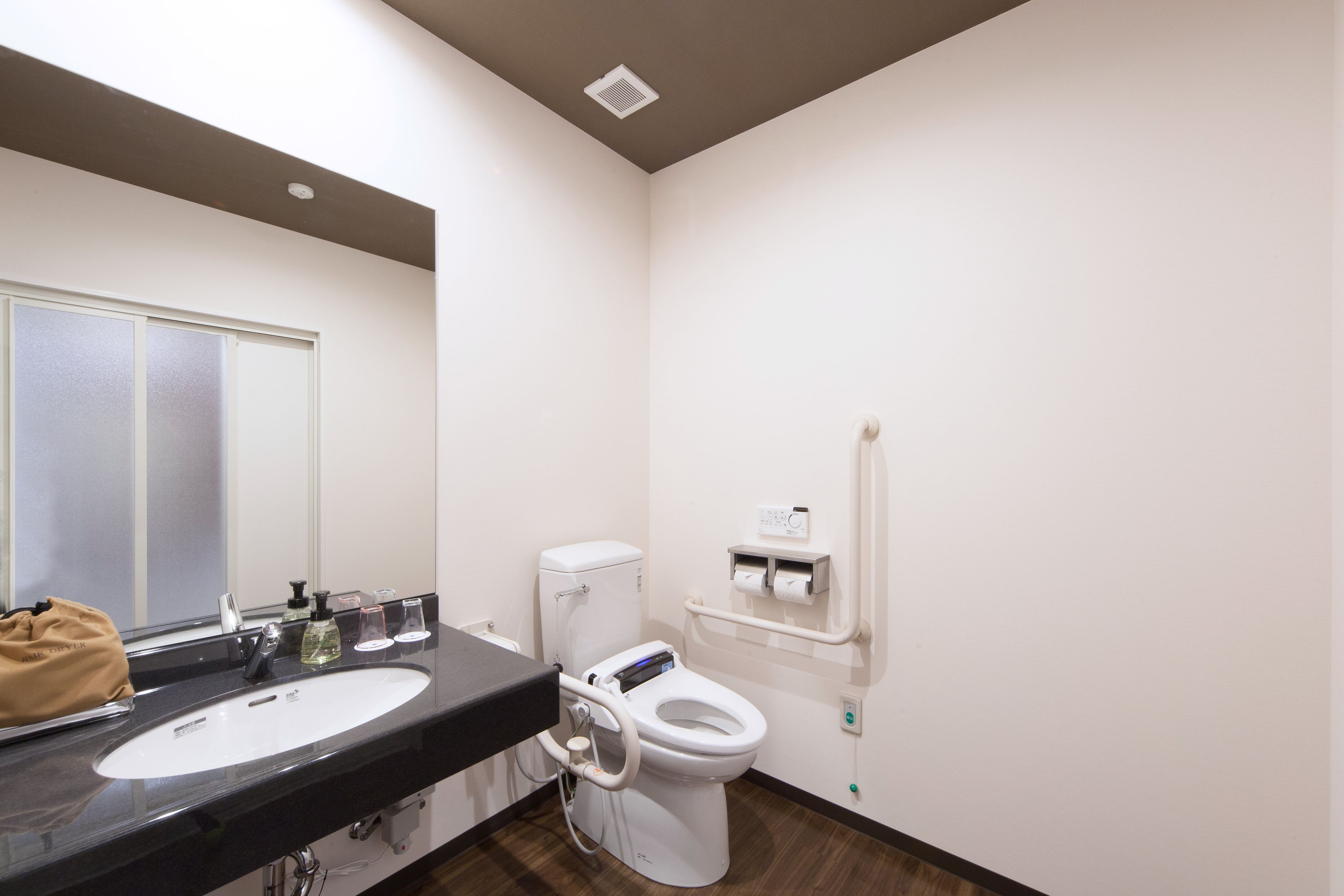 Une salle de bain moderne avec un lavabo noir, des toilettes blanches et un miroir.