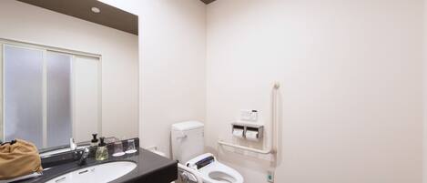 Une salle de bain moderne avec un lavabo noir, des toilettes blanches et un miroir.