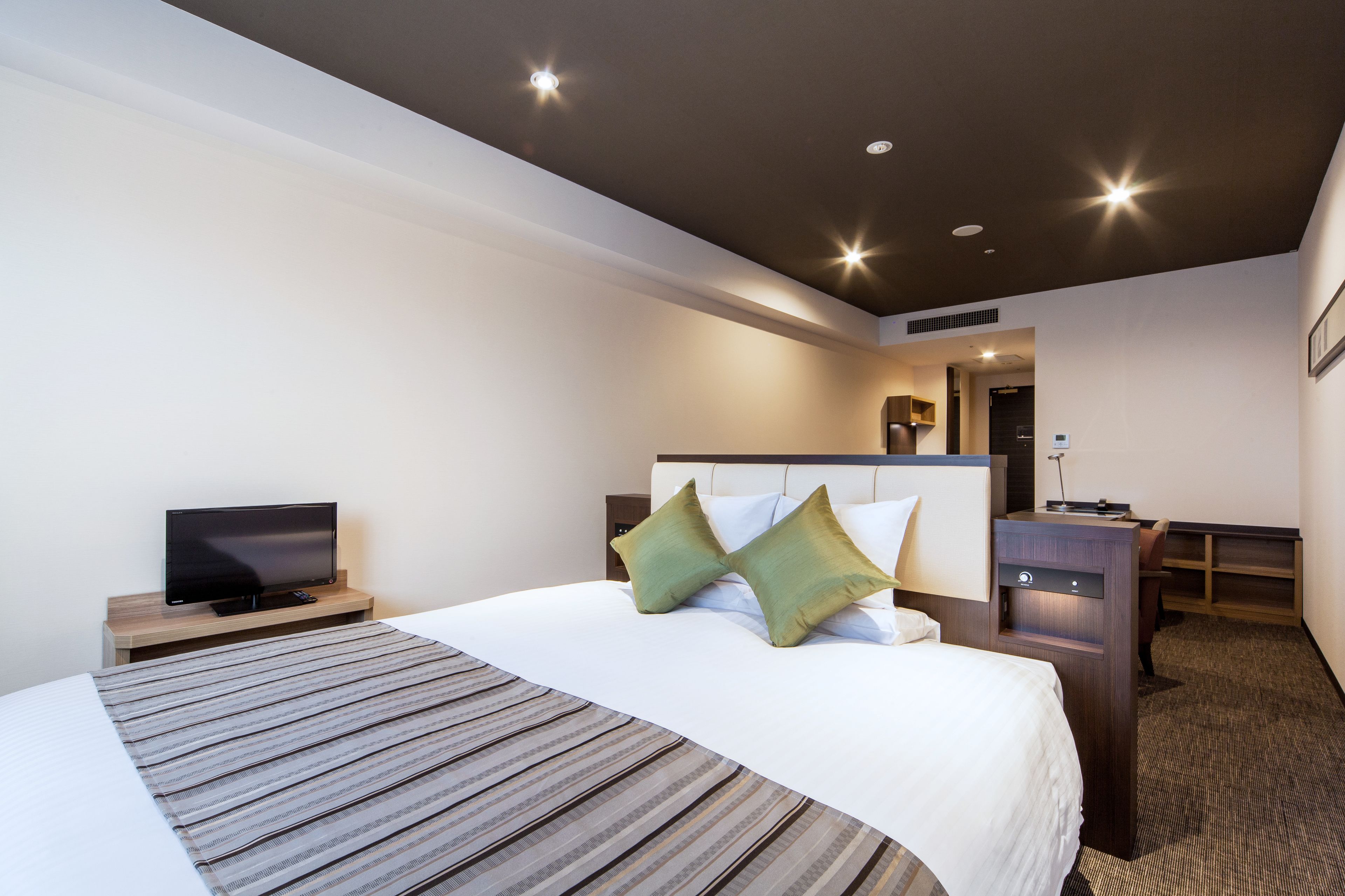 A hotel room with a large bed, a desk, a television, and a walk-in closet.