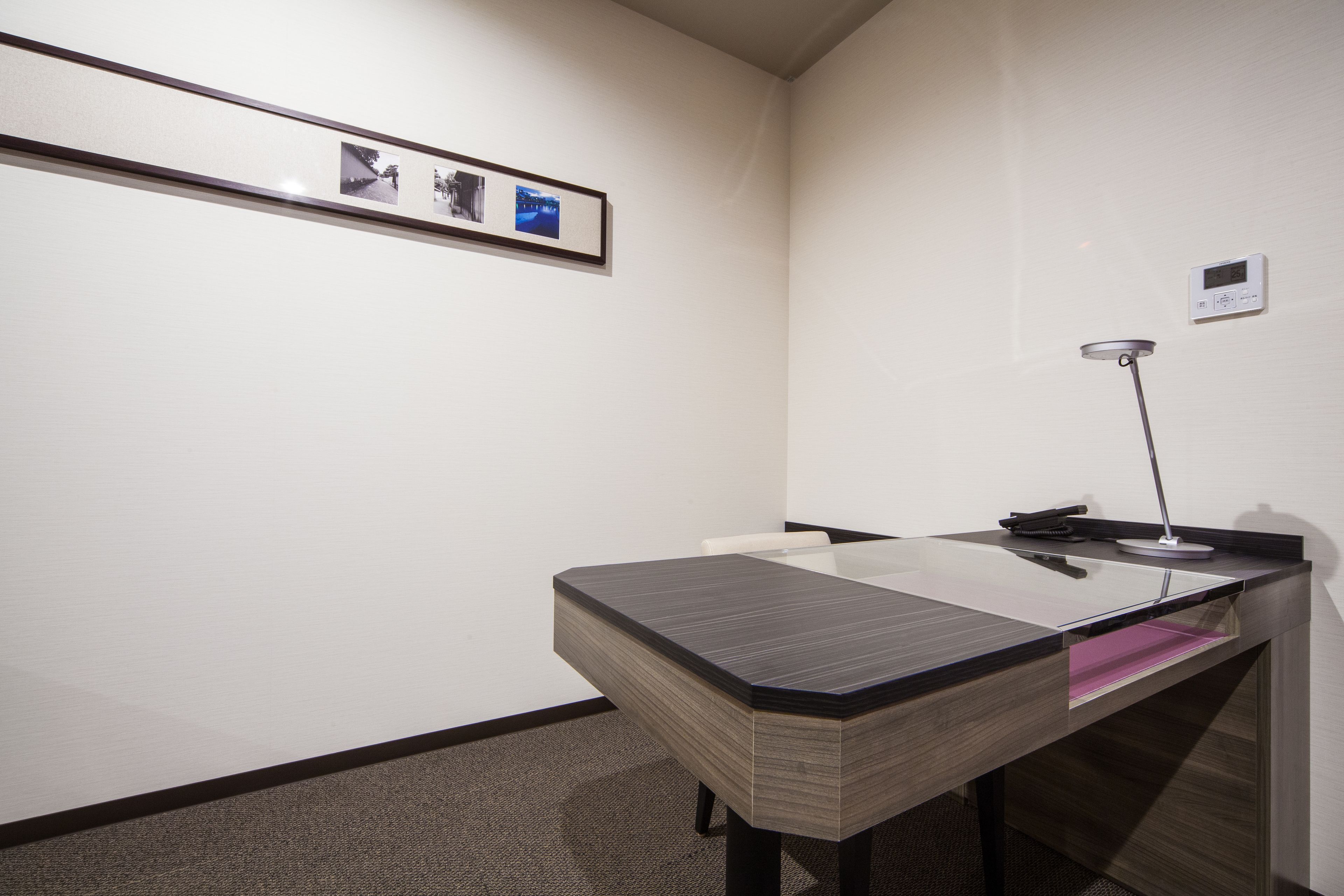 A modern office space with a desk, chair, and a framed photo on the wall.
