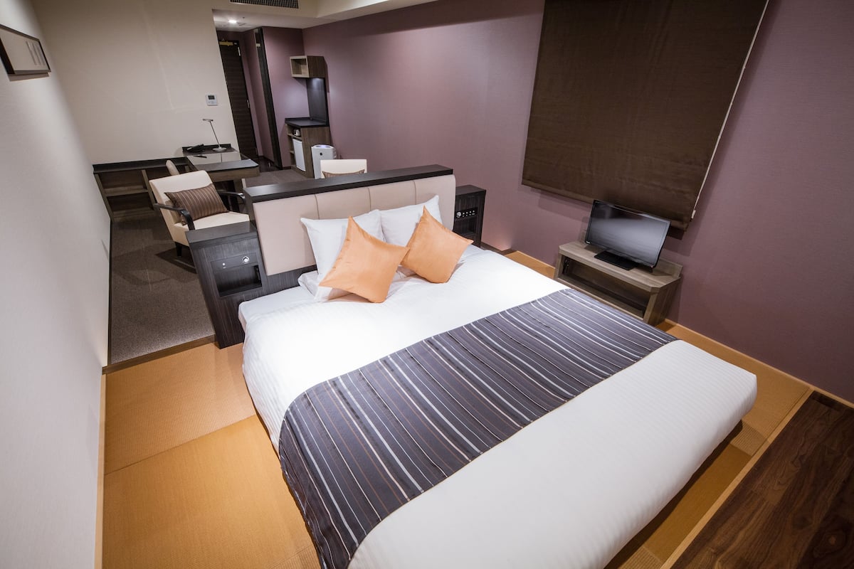 Moderni hotellihuone, jossa on suuri sänky, yöpöydät, työpöytä ja televisio.