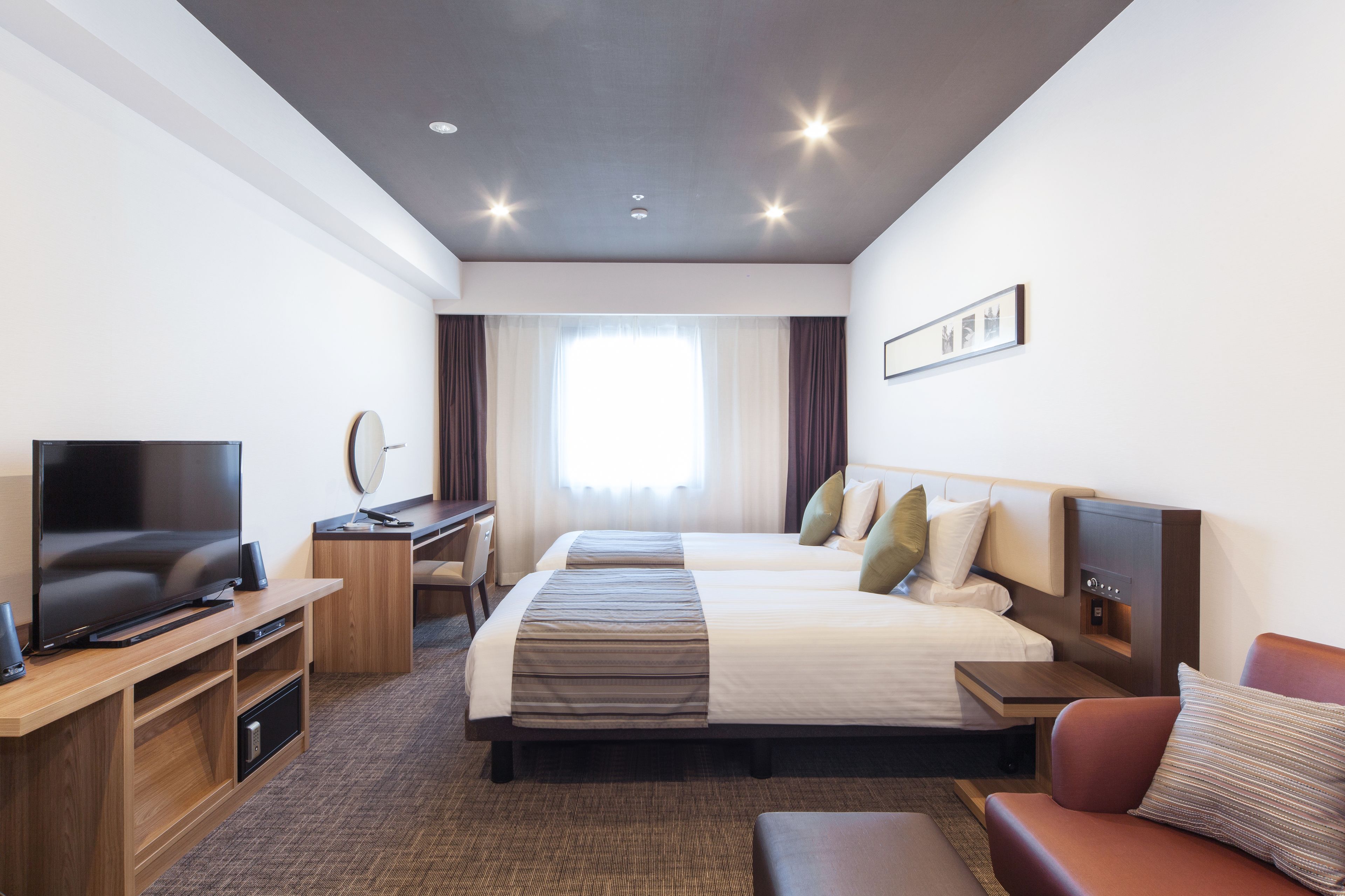 A hotel room with a large bed, a TV, a desk, and a couch.