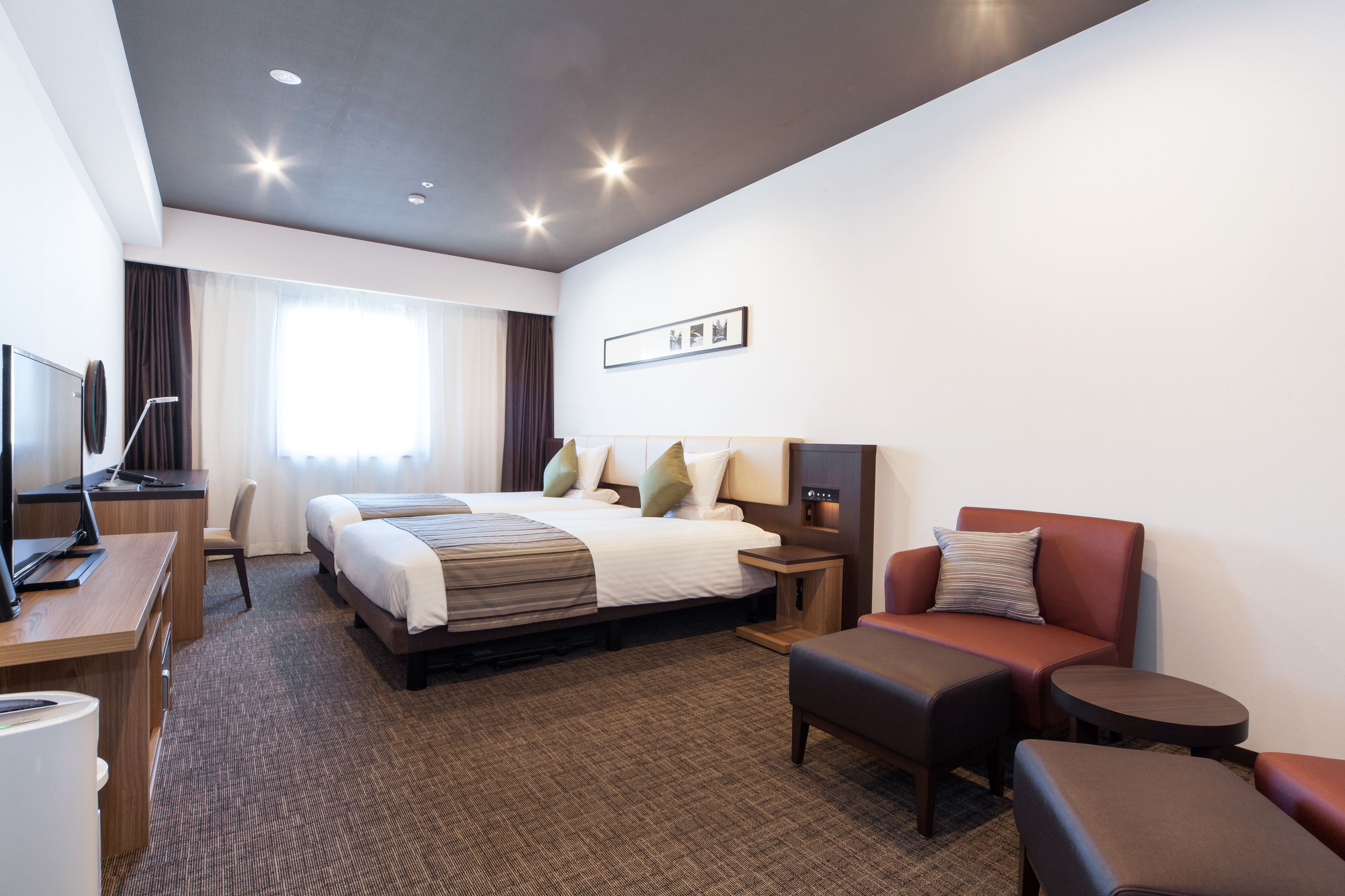 Een hotelkamer met een groot bed, een bureau met een computer, een stoel, een bank en een kleine tafel.