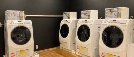 A laundry room with four washing machines lined up against a dark wall.
