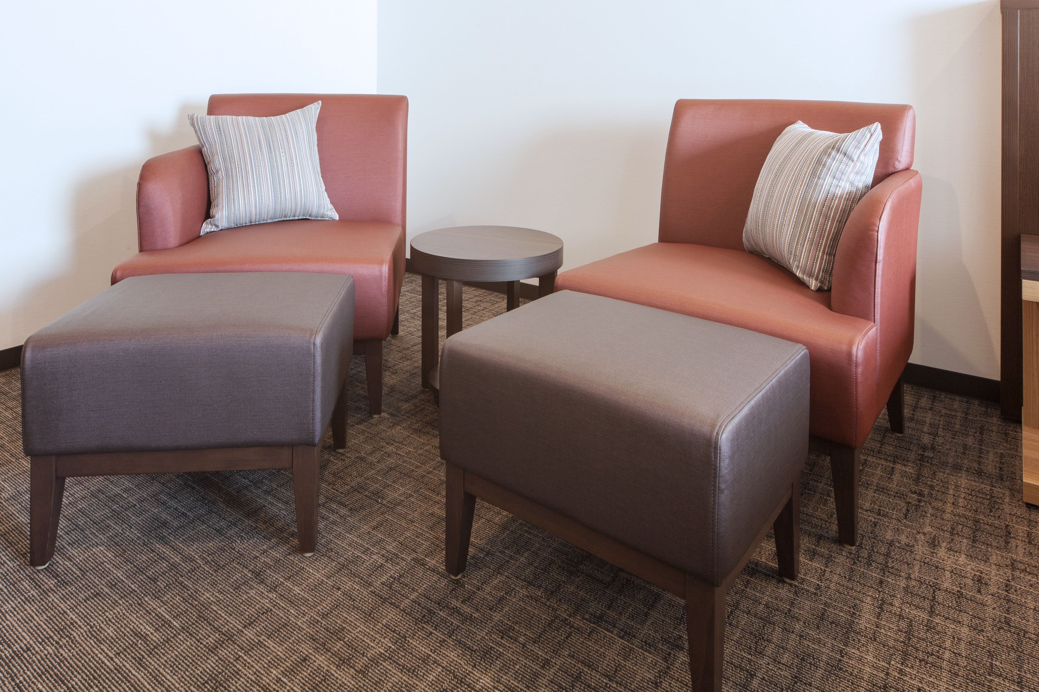 A room with two leather armchairs, a small round table, and two matching ottomans.