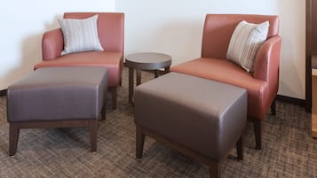 A room with two leather armchairs, a small round table, and two matching ottomans.