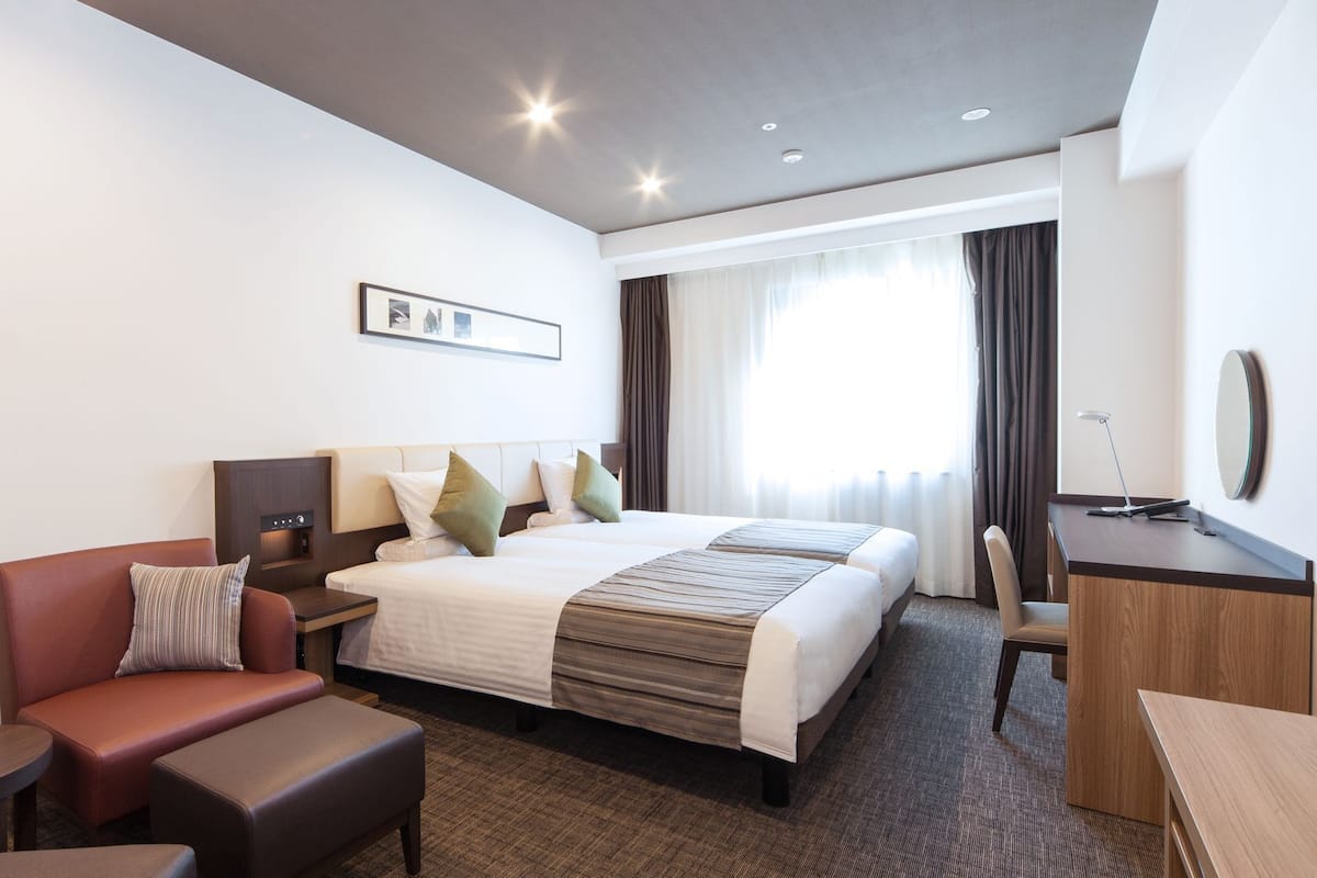 Hotellihuone, jossa on sänky, työpöytä, tuoli, sohva ja pieni pöytä.
