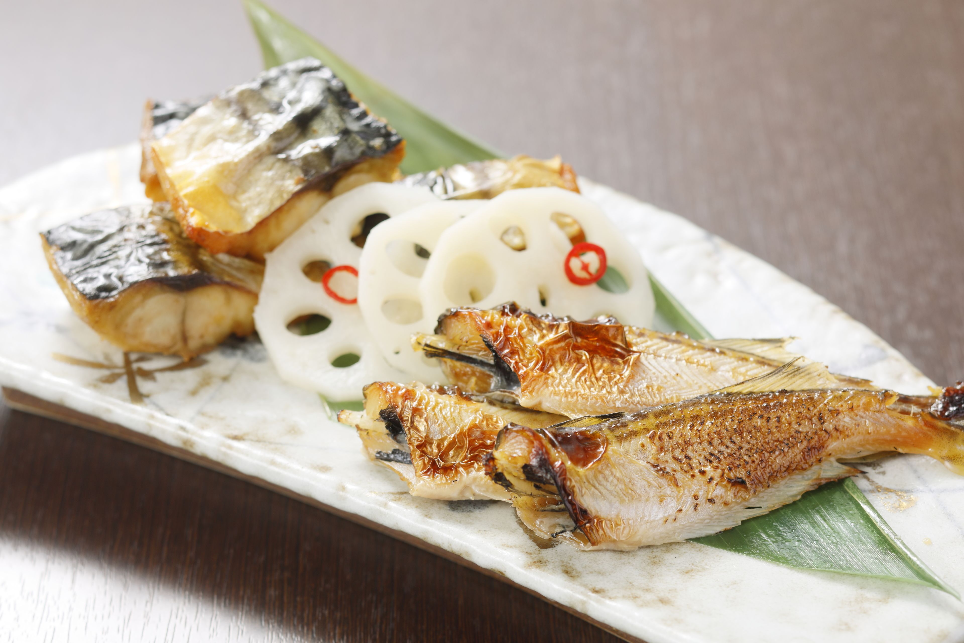 Ein Teller mit gegrilltem Fisch, Tofu und Lotuswurzelscheiben.