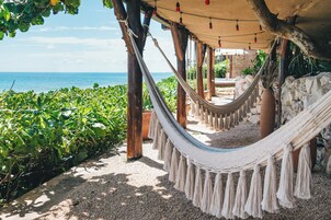 A hammock under a wooden structure with a view of the sea.