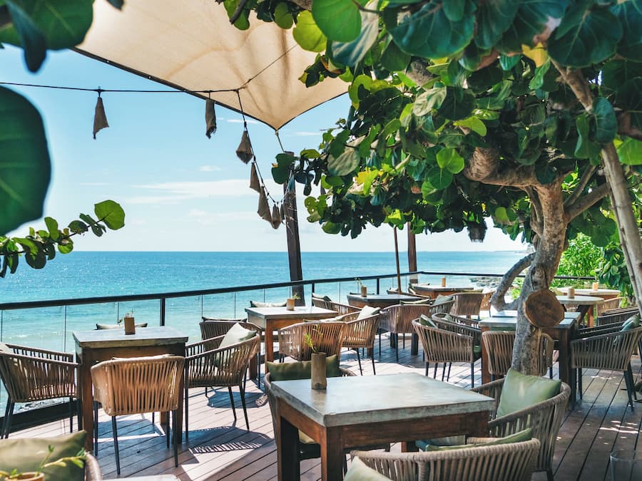 An outdoor seating area with tables and chairs, overlooking the sea.