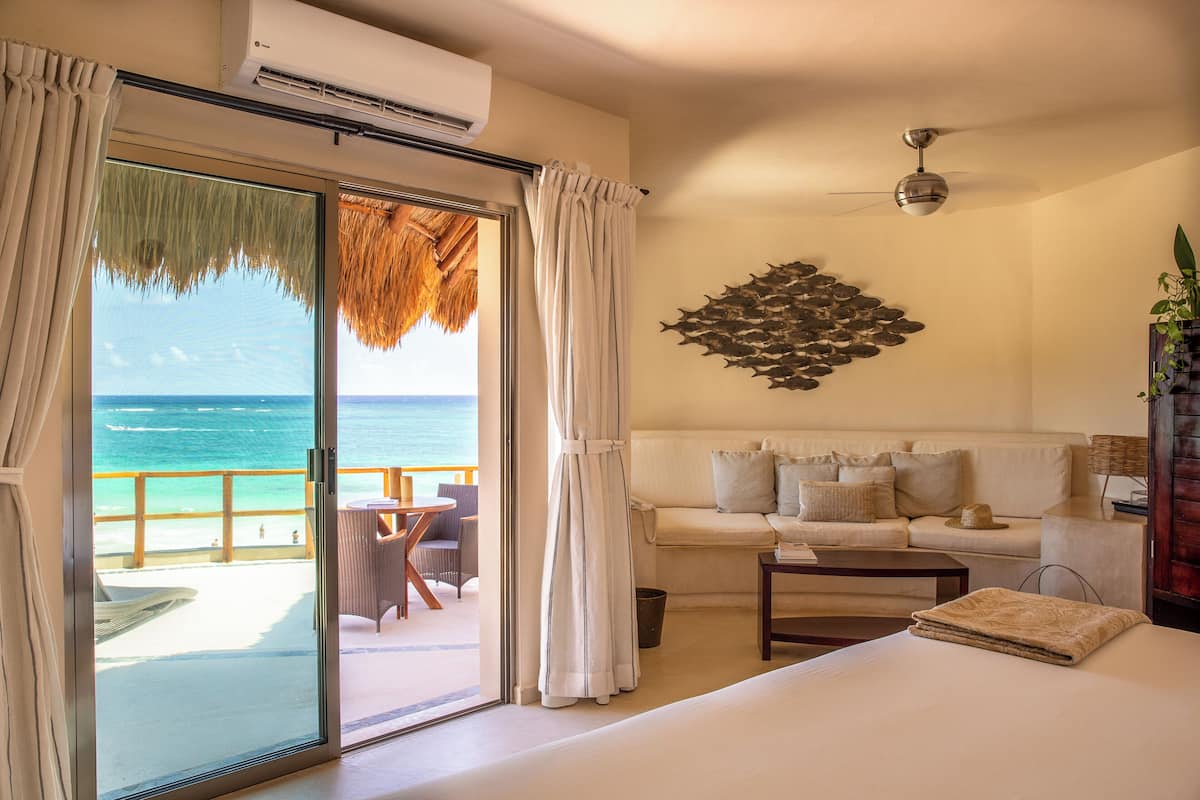 Ein Hotelzimmer mit Bett, Sofa, Esstisch und Meerblick.