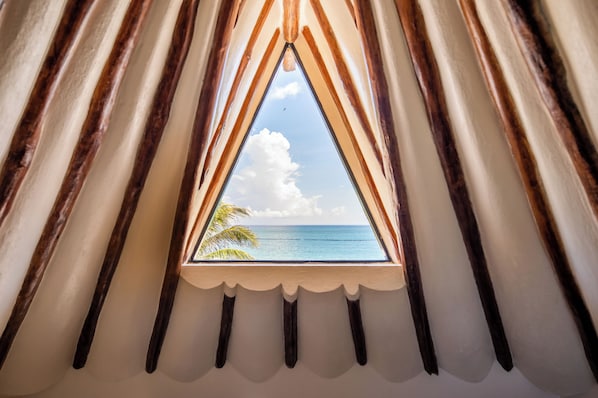 Ein Fenster mit Blick auf das Meer und eine Palme.