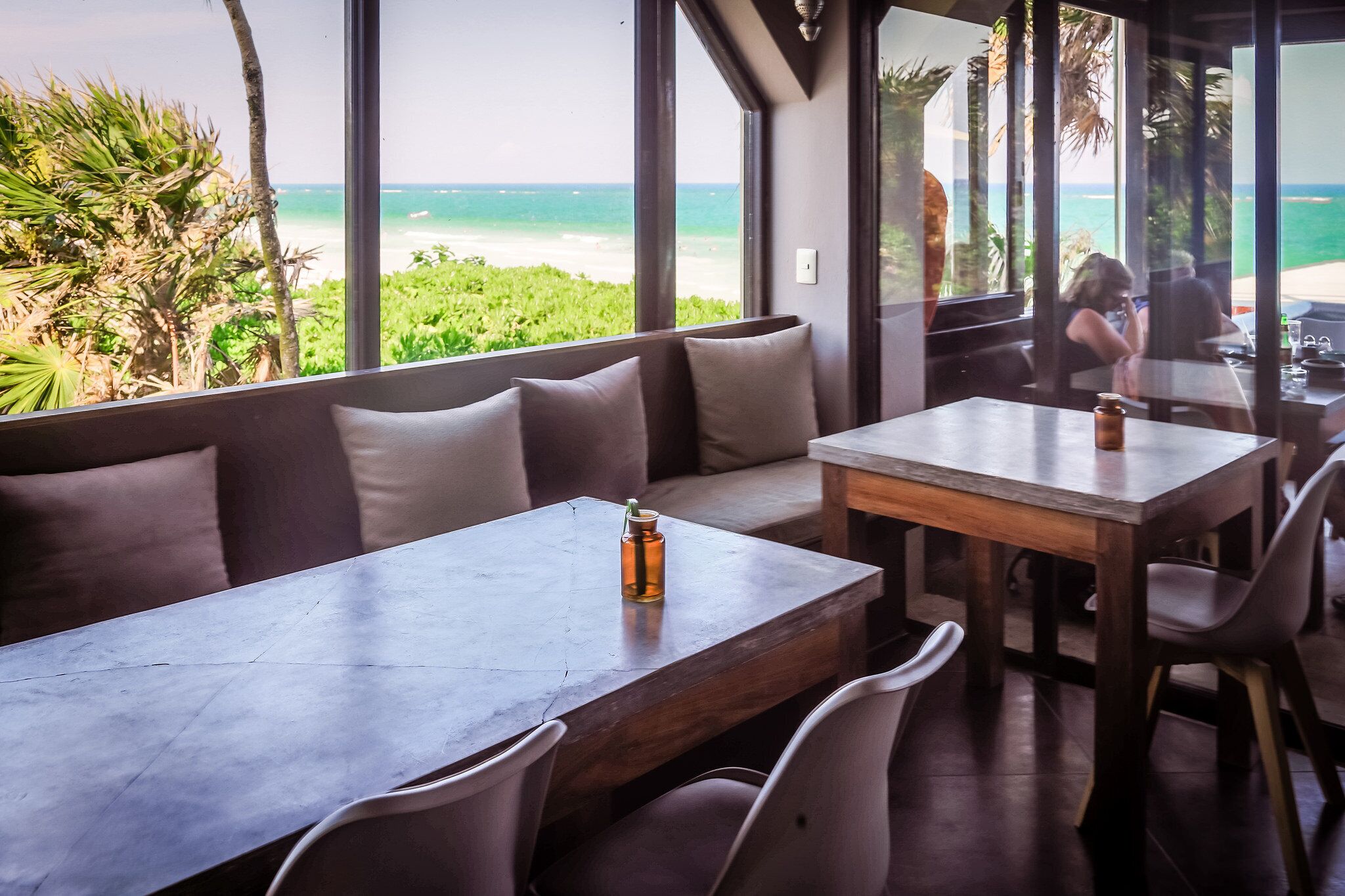 Un restaurante con vista al océano, que cuenta con una mesa larga y un banco acolchado.