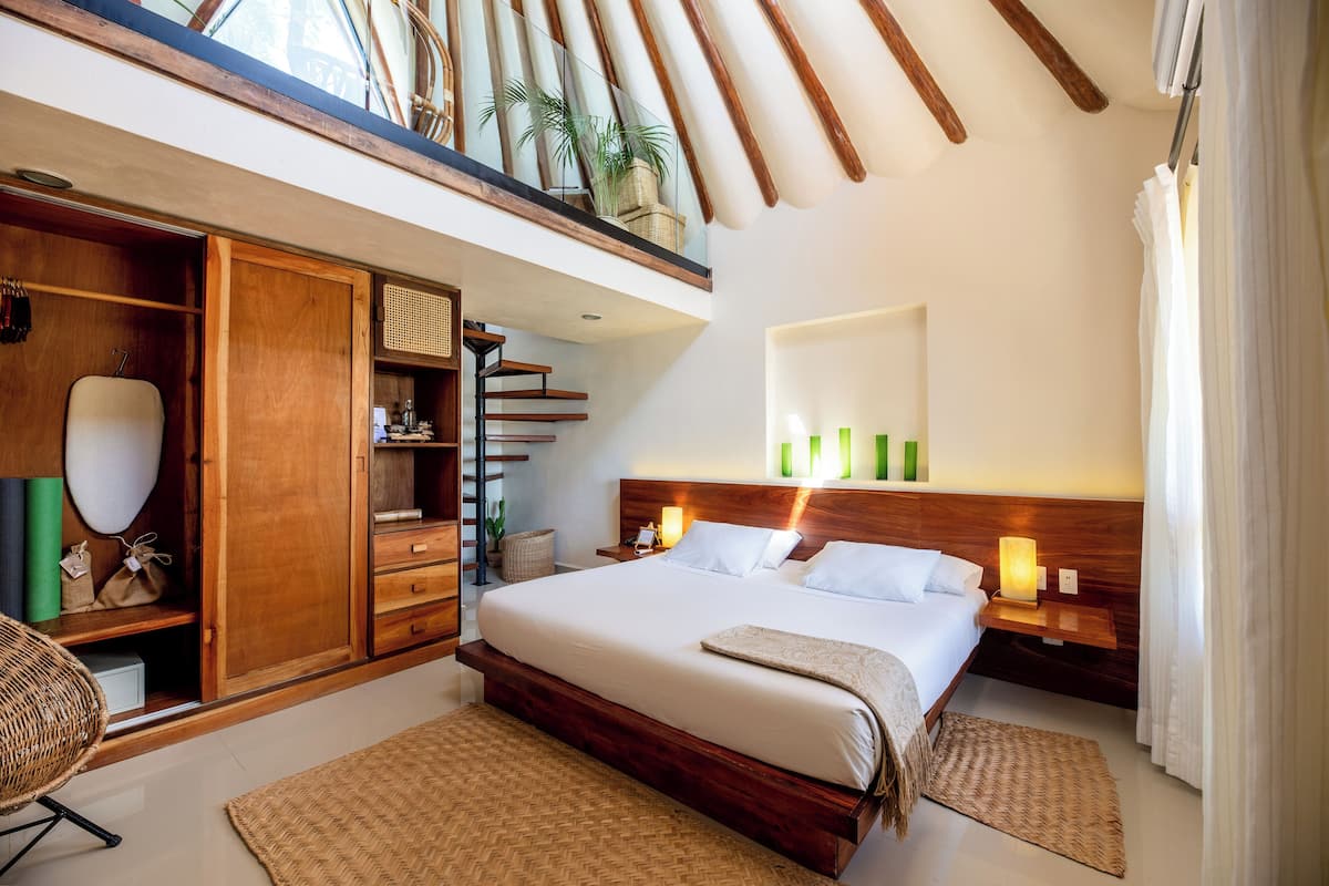 Ein geräumiges Schlafzimmer mit einem großen Bett, einem Holzschrank und einem Balkon mit Pflanzen.