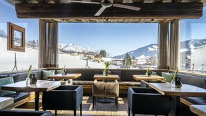 A restaurant with outdoor seating, wooden tables, and a view of snow-covered mountains. - mama thresl (Leogang)